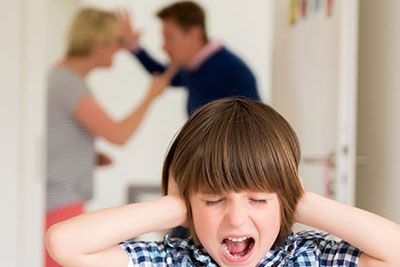 Child covering ears while parents argue